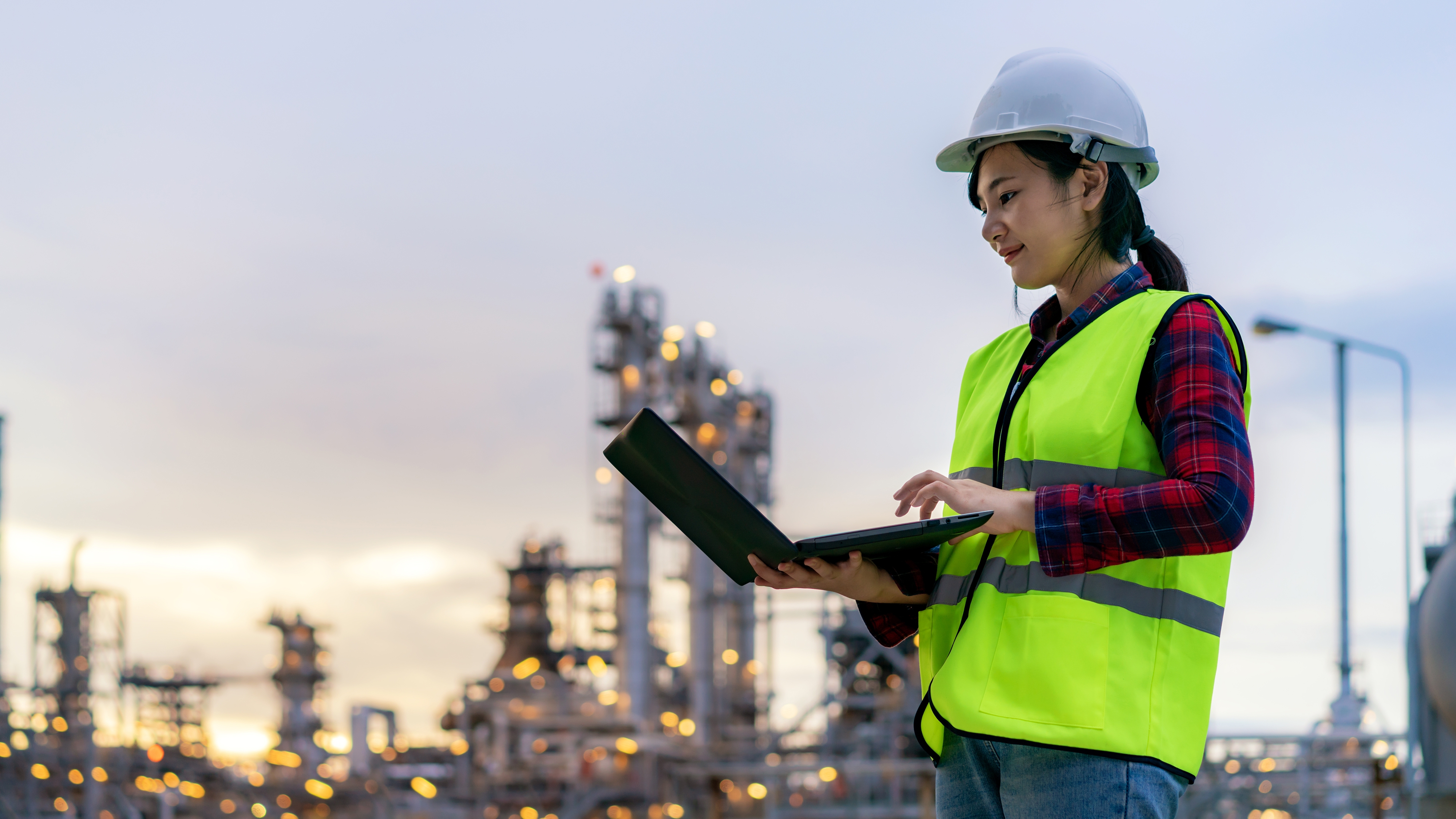 Asian woman petrochemical engineer working at night with notebook Inside oil and gas refinery plant industry factory at night for inspector safety quality control.